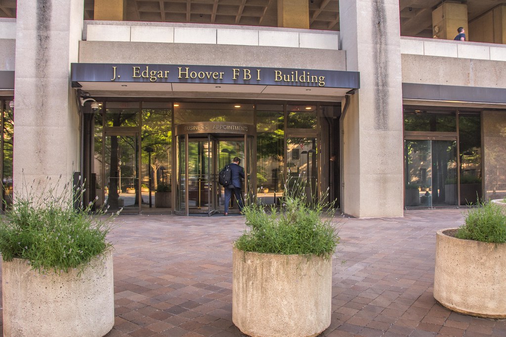 Fbi cuts domestic terror units as trump allies dismantle jan. 6 aftermath 1 The entrance of the j. Edgar hoover fbi building in washington, d. C. , featuring a revolving glass door with a man in a suit entering the building. Large concrete planters with green shrubs line the walkway.